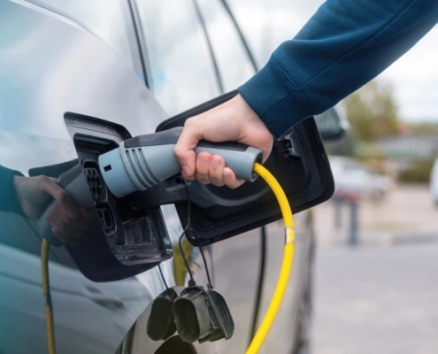 Persona conectando un cargador a un auto eléctrico en una estación de carga, representando el crecimiento de la electromovilidad en México