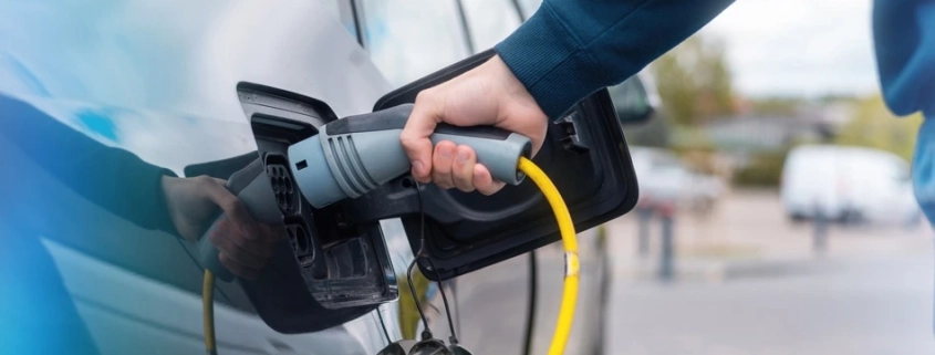 Persona conectando un cargador a un auto eléctrico en una estación de carga, representando el crecimiento de la electromovilidad en México