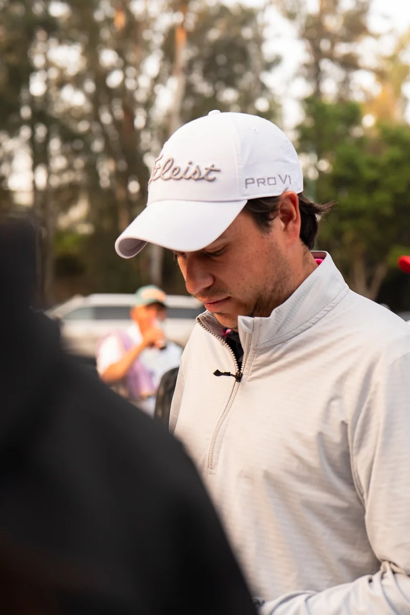 Jugador con gorra blanca mirando hacia abajo mientras espera su turno en el registro del torneo.
