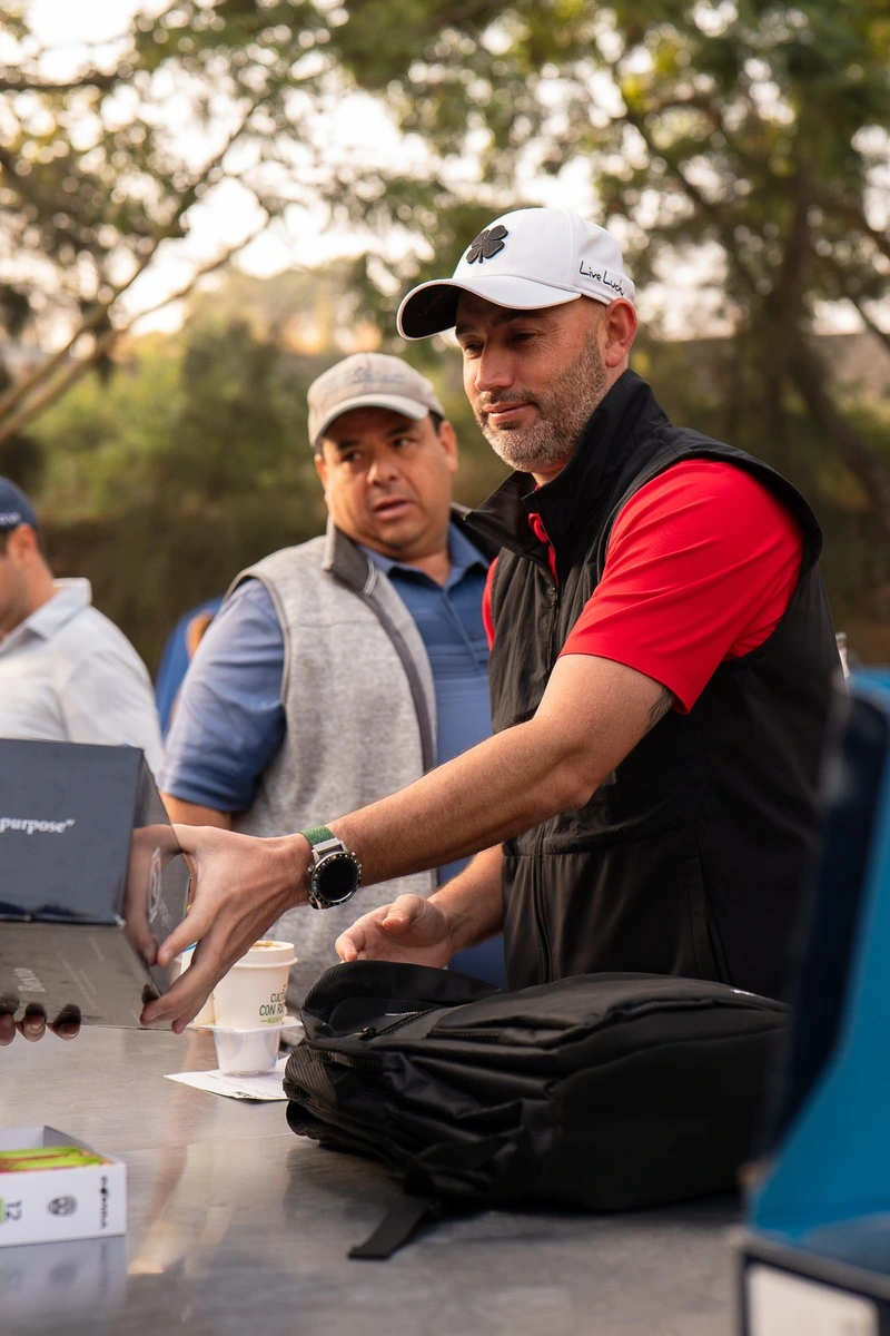 Hombre con gorra blanca recibe su kit de bienvenida en el módulo de registro del torneo