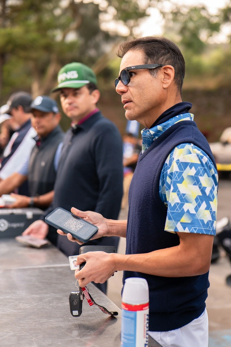 Hombre con gafas mostrando un código QR en su celular durante el registro del evento de golf