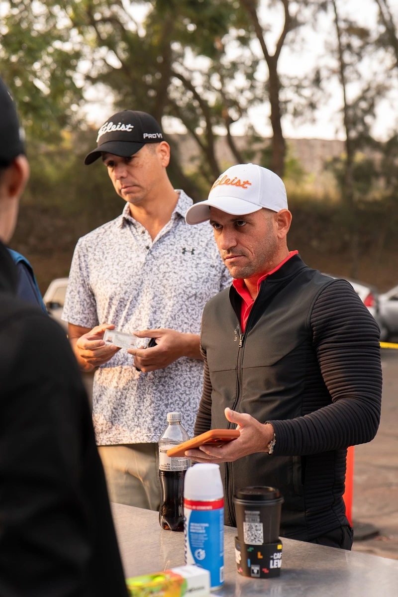 Dos jugadores muestran documentos y celular durante el proceso de registro del torneo de golf