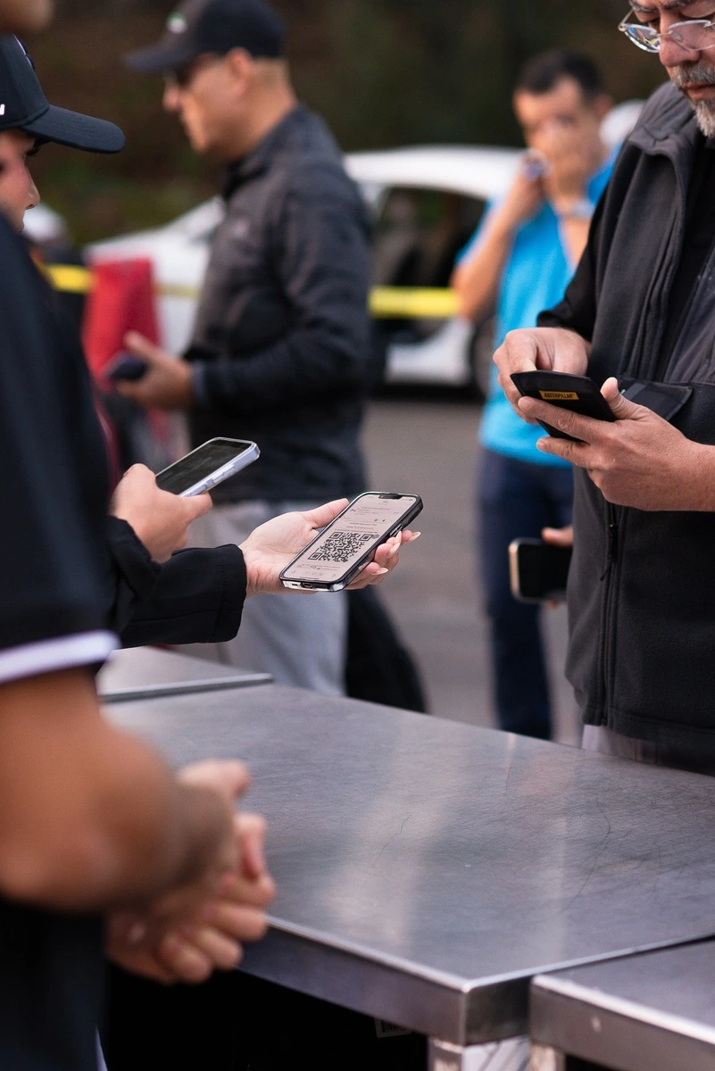 Participantes muestran códigos QR en sus teléfonos durante el registro del torneo de golf