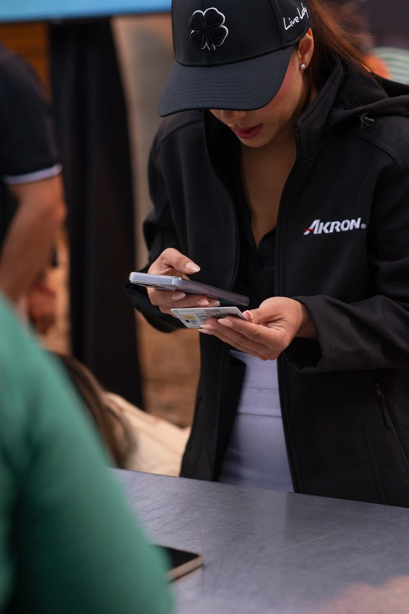 Mujer del staff revisando identificación y datos en su teléfono durante el registro