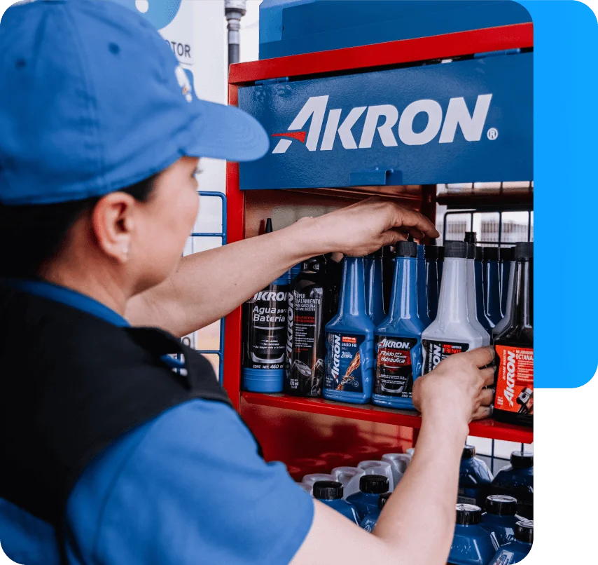 Distribuidor Akron seleccionando productos químicos de estantería de exhibición con logo Akron.