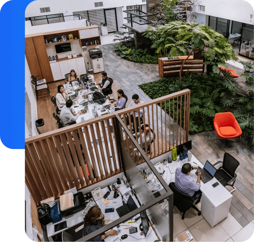Equipo trabajando en espacio de coworking moderno con dos niveles y áreas verdes.