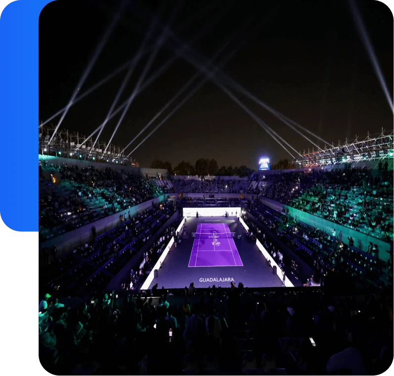 Aerial view of illuminated tennis court at night with light beams during Guadalajara Open.