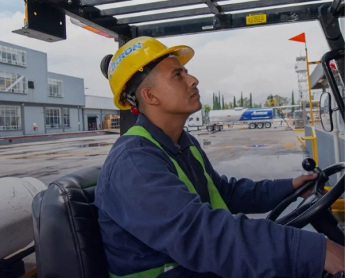 Operador Akron con equipo de seguridad operando maquinaria en sitio de construcción.
