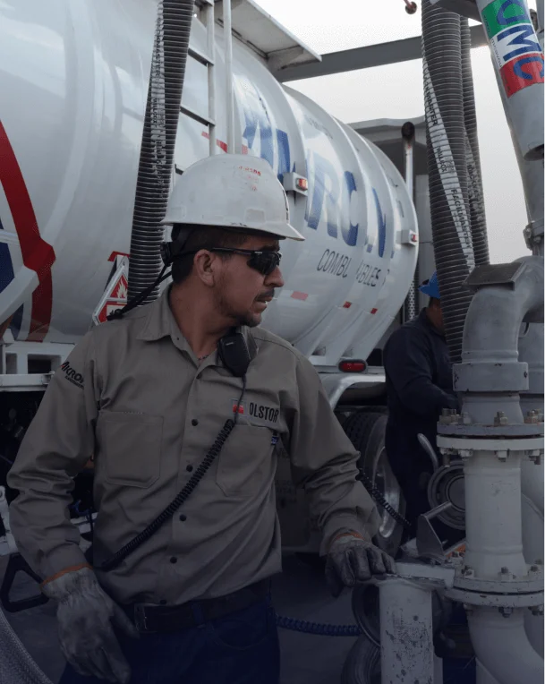 Técnico con equipo de seguridad trabajando en camión cisterna de transporte químico.