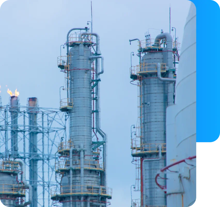 Torres de destilación en refinería petroquímica con llama de quemador encendida.